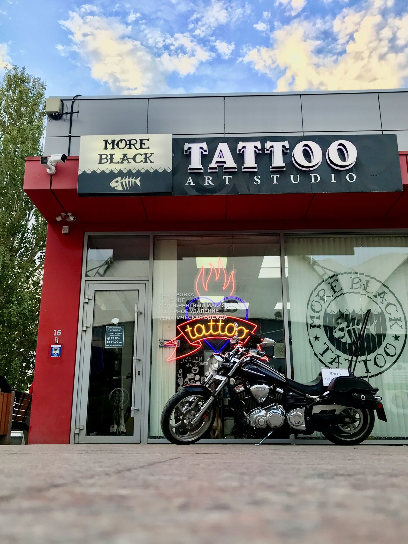 Фасад студии More Black Tattoo на набережной Анапы: вывеска, неон tattoo и мотоцикл у входа